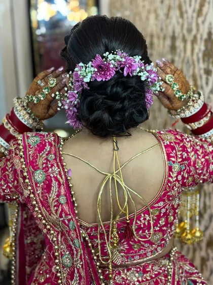 A detailed shot of a beautiful bridal bun adorned with fresh purple and white flowers. This showcases the hairstyling skills that complete the perfect bridal look.