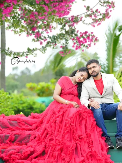A romantic couple's portrait on green steps, with the mother-to-be in a red ruffled gown.