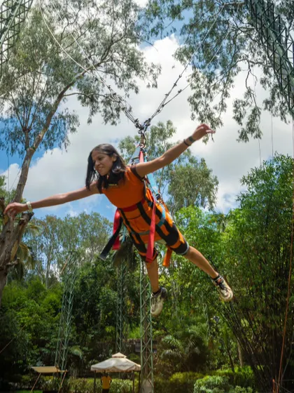 A young adventurer enjoying the Superman Swing, flying through the air with arms outstretched.