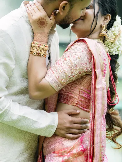 An intimate kiss, with a focus on the bride's beautiful henna and traditional attire.