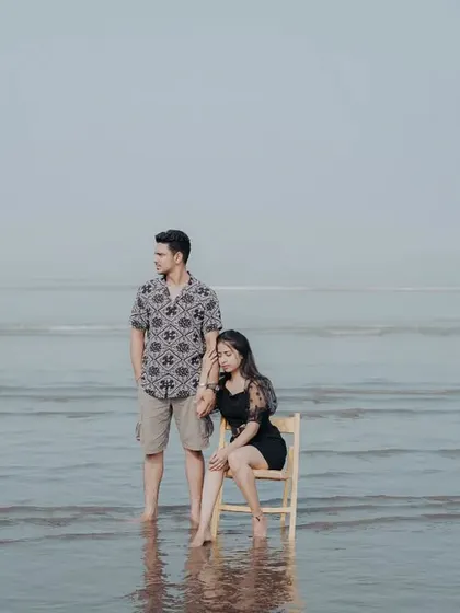 An artistic pre-wedding portrait using a chair prop in the water, giving the image a surreal and thoughtful quality.