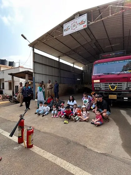 A firefighter gives a safety demonstration to our students, who are sitting attentively in front of the fire station.
