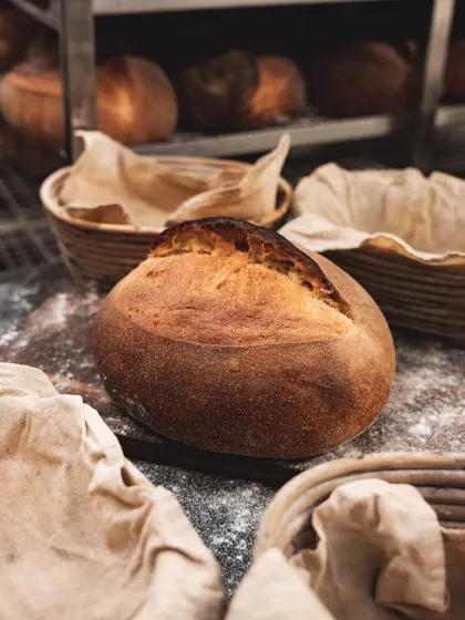 A finished sourdough loaf, ready to be sliced for our sandwiches or sold at our deli. The rustic, crackled crust is just as delicious as the soft interior.