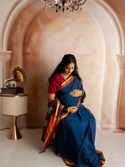 A classic portrait in a traditional blue Maharashtrian saree. The vintage props like the gramophone add a nostalgic and timeless charm.