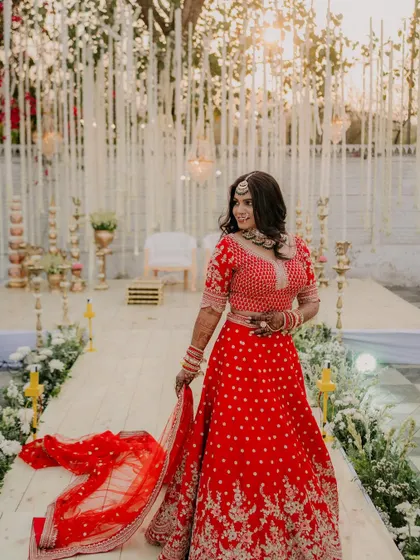 The bride walking down the aisle, her red lehenga flowing beautifully. The makeup is designed to look perfect in motion and from every angle.