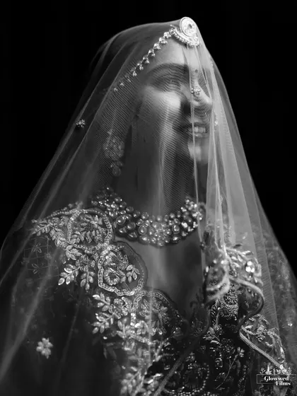 An artistic black and white portrait of the bride smiling behind her veil, creating a beautiful and mysterious effect.