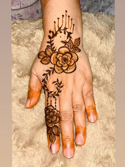 A simple and sweet rose design. This minimalist piece features a single rose with a leafy vine, perfect for guests or anyone wanting a small, elegant touch of henna.