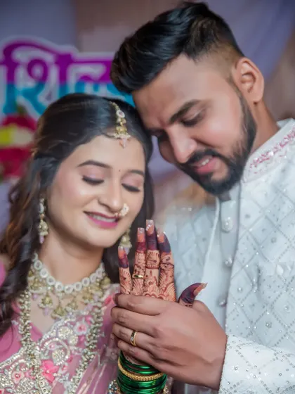 The groom-to-be admires the henna and the new ring on his fiancée's hand, a small but meaningful gesture of love.