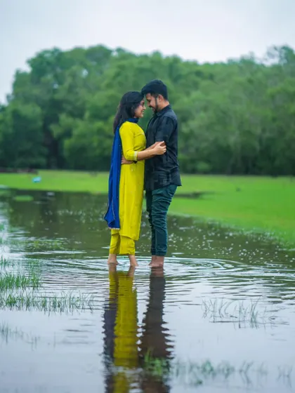 A romantic pre-wedding shot of a couple standing in a flooded meadow. The reflection in the water and the greenery create a beautiful, serene atmosphere for this intimate portrait.
