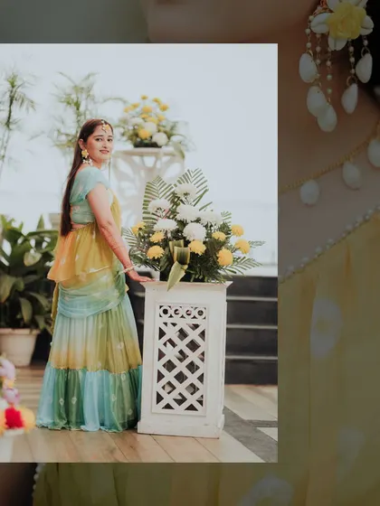 A full-length portrait of the bride in her multi-colored Haldi lehenga. The photo highlights her beautiful outfit and the simple, elegant decor.