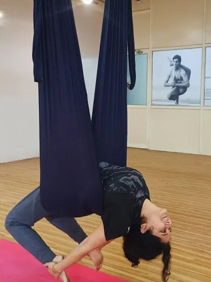A student performs a graceful backbend while suspended in the aerial hammock. This pose beautifully opens the heart and shoulders, demonstrating the elegance of aerial practice.