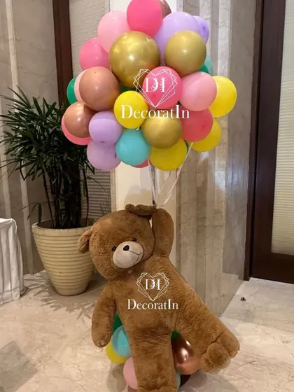 A giant teddy bear holding a colorful bunch of balloons adds a cuddly and whimsical touch to the party decor.