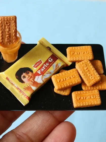A close-up of a Parle-G biscuit miniature with a tiny cup of chai, a nostalgic and beloved combination.