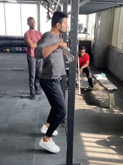 A coach practices a movement in the squat rack while I observe. These practical application moments are where the real learning happens.