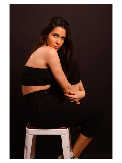 A minimalist and modern fashion portrait. The simple black outfit and dark background create a sleek and sophisticated look.
