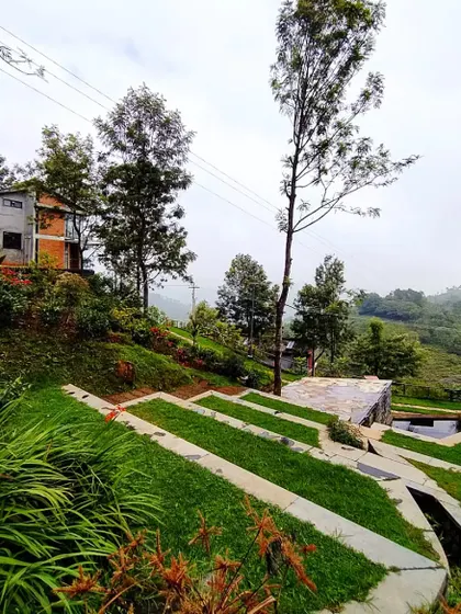 A view of the landscape design at VAY, Hulical, showing terraced lawns and water channels that manage rainwater flow on a sloped site. This project integrates public space, water management, and residential villas.