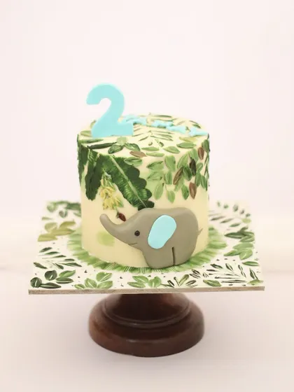 A sweet baby elephant cake for a second birthday. The jungle leaves are all hand-painted with a palette knife, and the little elephant is sculpted from fondant. I love how the painted cake board completes the look.
