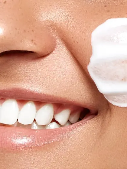 An extreme close-up focused on a smile and a swatch of creamy product. This shot effectively communicates a feeling of joy and satisfaction while simultaneously showing the rich texture of a face cream or cleanser.