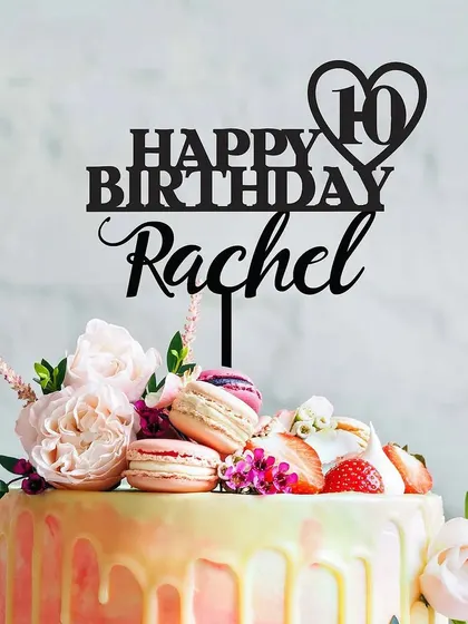 A vibrant drip cake loaded with fresh flowers and colorful macarons, topped with a custom "Happy 10th Birthday Rachel" sign. This style is great for anyone who loves a burst of color and flavor.