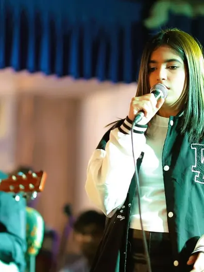 A vocalist and guitarist share the spotlight. Our program encourages different combinations of instruments and voices, helping students learn to arrange and perform songs together.