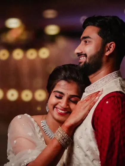 A romantic reception photo with a beautiful bokeh background. The bride's serene smile as she embraces her groom creates a warm and dreamy atmosphere.