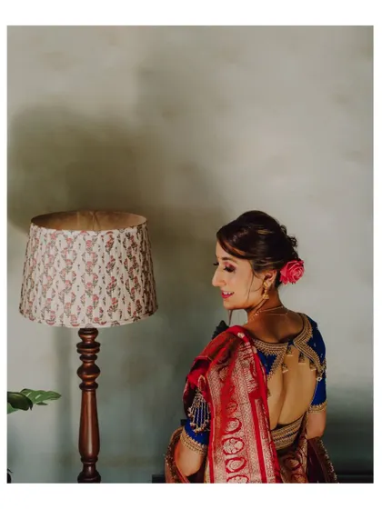 A beautiful back-shot of a Maharashtrian bride, showing off her intricate hairstyle with a rose and the design of her blouse.