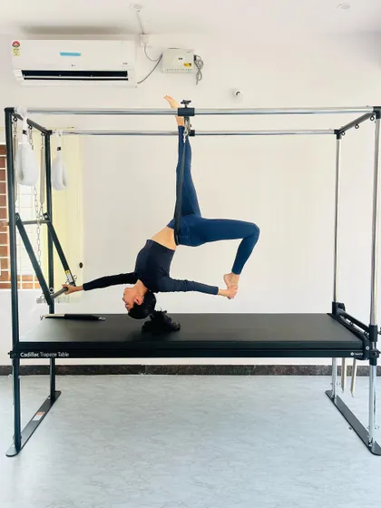 A graceful backbend pose suspended from the Cadillac, highlighting spinal mobility and control.