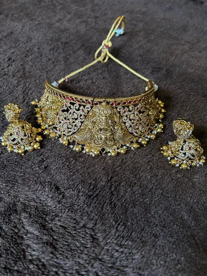 A close-up of a Lakshmi temple choker with an antique finish and pearl detailing. This is a very popular rental piece for its traditional design.