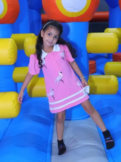 A girl poses on a colorful inflatable structure, ready for a day of play.