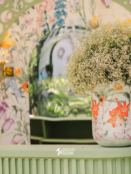 A detail shot showing the layers of pattern and texture, from the floral-print vase to the custom-printed wallpaper in the background.