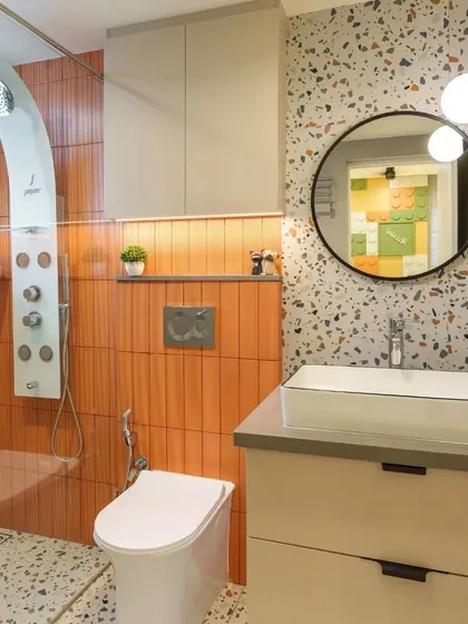 I transformed this kid's bathroom into a whimsical space with playful orange accents and terrazzo tiles, while modern fixtures ensure functionality.