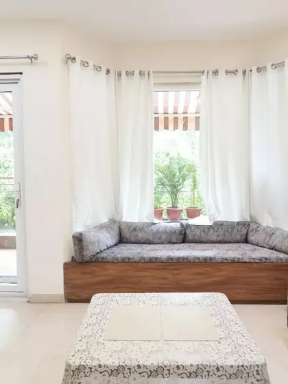 A cozy window seating area with a wooden base and plush grey cushions, providing a perfect spot for reading or enjoying the view.