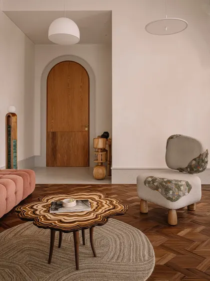 A detail shot in the daughter's bedroom, featuring a unique chair with stone-like upholstery and a layered wood coffee table, showcasing our love for bespoke, artistic furniture.
