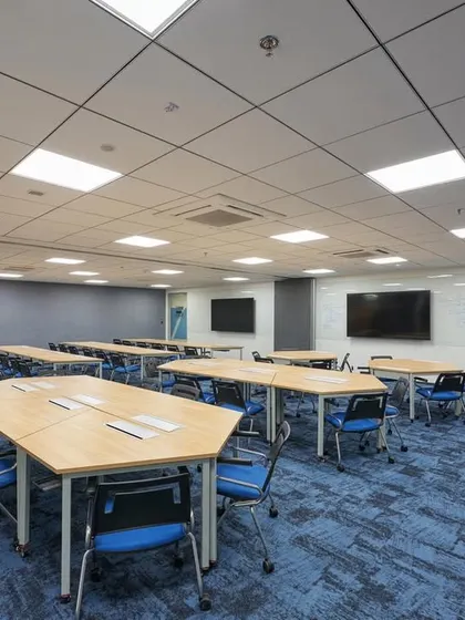 A flexible training room with reconfigurable tables that can be arranged in different layouts for workshops, presentations, or group work.