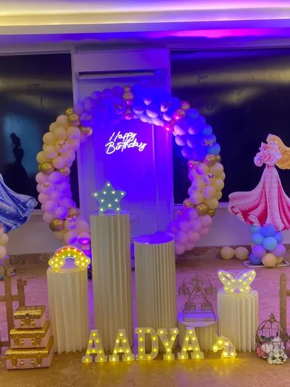 A grand Disney Princess themed party featuring Cinderella, Sleeping Beauty, and Sofia the First. The setup includes a large circular balloon arch and a white picket fence.