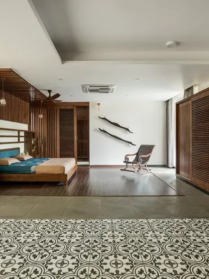 The master bedroom is a spacious retreat, featuring a mix of wood paneling, patterned floor tiles, and clean white walls. The design separates the sleeping area from a lounge space, creating a private suite.