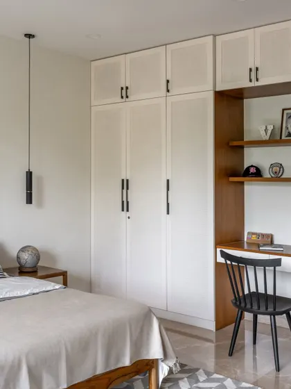 This bedroom includes a built-in desk and shelving unit, making it a multifunctional space for both rest and work. The clean lines and neutral palette keep the room feeling calm and organized.