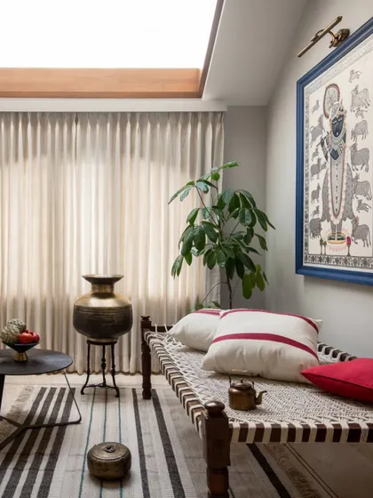 From the same AD India feature, this is the prayer room, lit by an expansive skylight. The space features a traditional Indian 'charpoy' daybed, Pichwai art, and antique brass artifacts.