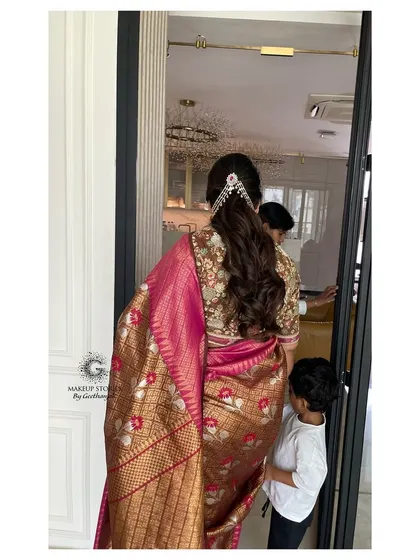 A view of Revathi's elegant hairstyle and the back of her saree. The makeup and hair work together to create a complete and polished look from every angle.