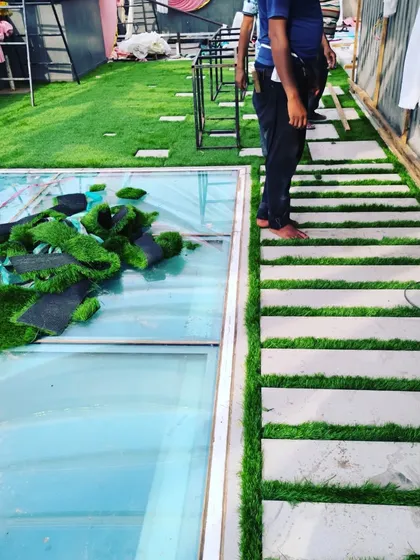 Here you can see the installation process, laying down lush 50mm artificial grass around a glass skylight feature on the terrace.