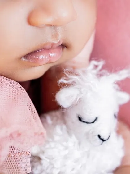 A macro shot focusing on the perfect lips of a newborn and their tiny toy. These detailed images capture the features you never want to forget.