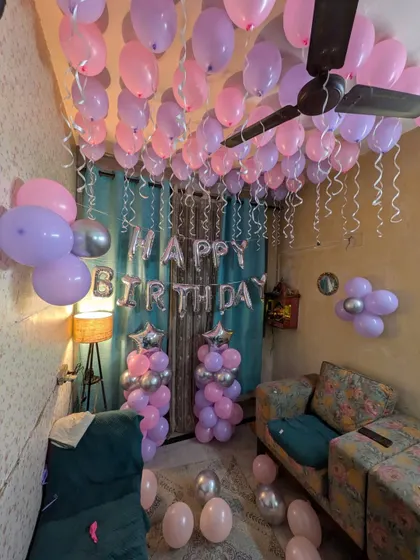 The setup includes balloon bouquets on the walls and pillars flanking the "Happy Birthday" sign.