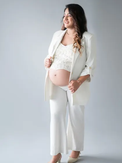 A full-length shot showcasing the chic, all-white maternity outfit. This look is both powerful and feminine, perfect for a contemporary maternity photoshoot.