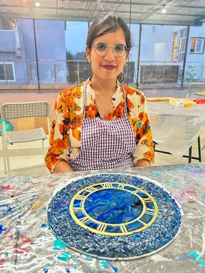A guest with her stunning blue geode resin clock, a piece she crafted herself in our workshop.