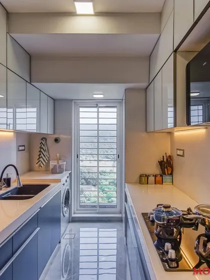 A parallel kitchen design that combines white upper cabinets with blue lower cabinets, creating a striking contrast. This space includes a dedicated spot for a washing machine, showing our focus on practical solutions.