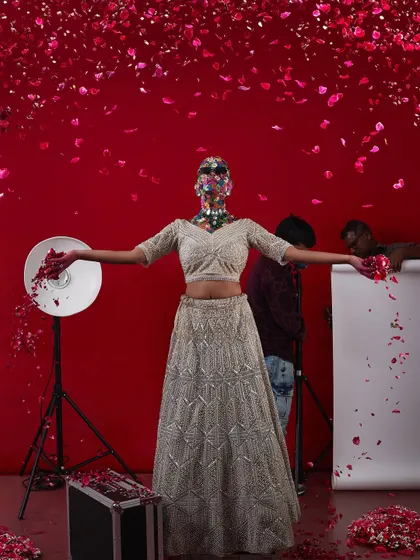 A creative and artistic bridal shot, with the model's face covered in flowers, set against a backdrop of falling petals.