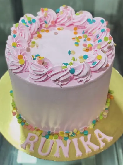 A simple and joyful pink cake with colorful sprinkles, personalized for Runika.