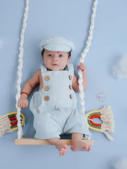 A seated perspective on the swing, this pose is perfect for capturing a calm, awake newborn in a creative setting.