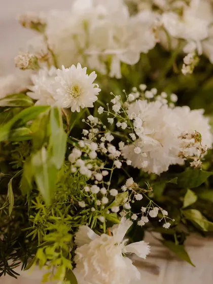 A macro shot of a delicate floral arrangement, focusing on the textures of white chrysanthemums and baby's breath. We believe that beauty lies in the details, and we ensure every floral element is perfect.