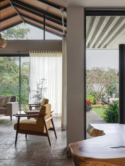 The living and dining areas of Grove House are designed as one continuous, open space that flows out onto the patio. This perspective shows the seamless transition from the high-ceilinged interior to the garden, a hallmark of our tropical modern architecture.
